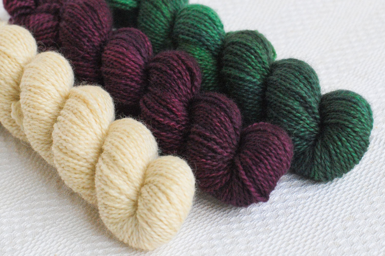 Set of three hand-dyed mini-skeins in natural, burgundy, and dark green