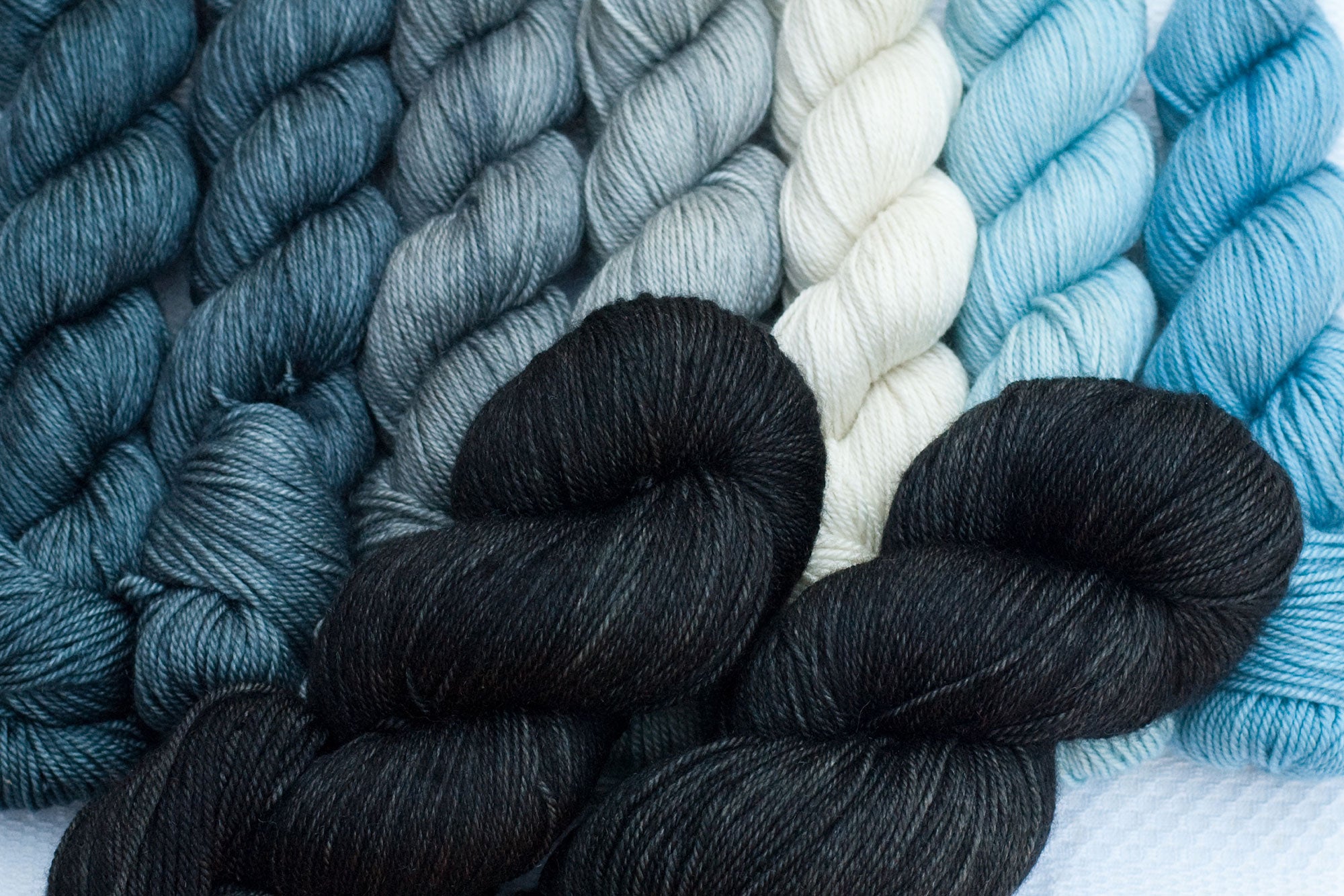 mountain musings mkal hand-dyed yarn set with black main colour and grey, white and blue contrast gradient set