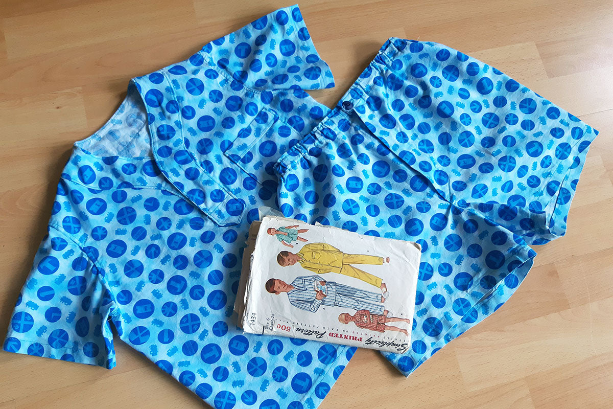 Flat lay of handmade boys summer pajamas in blue print with vintage sewing pattern resting on top