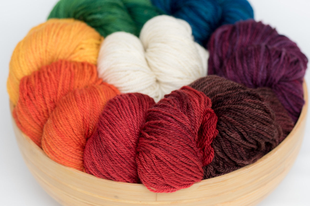 Several skeins of brightly coloured Norwood yarn in a wooden bowl