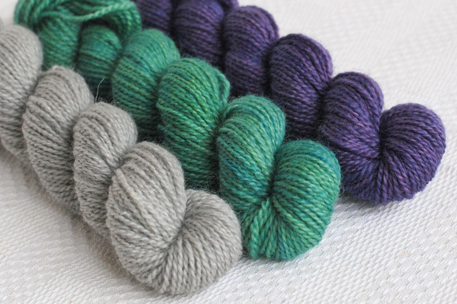 Set of three hand-dyed mini-skeins in grey, teal, and purple