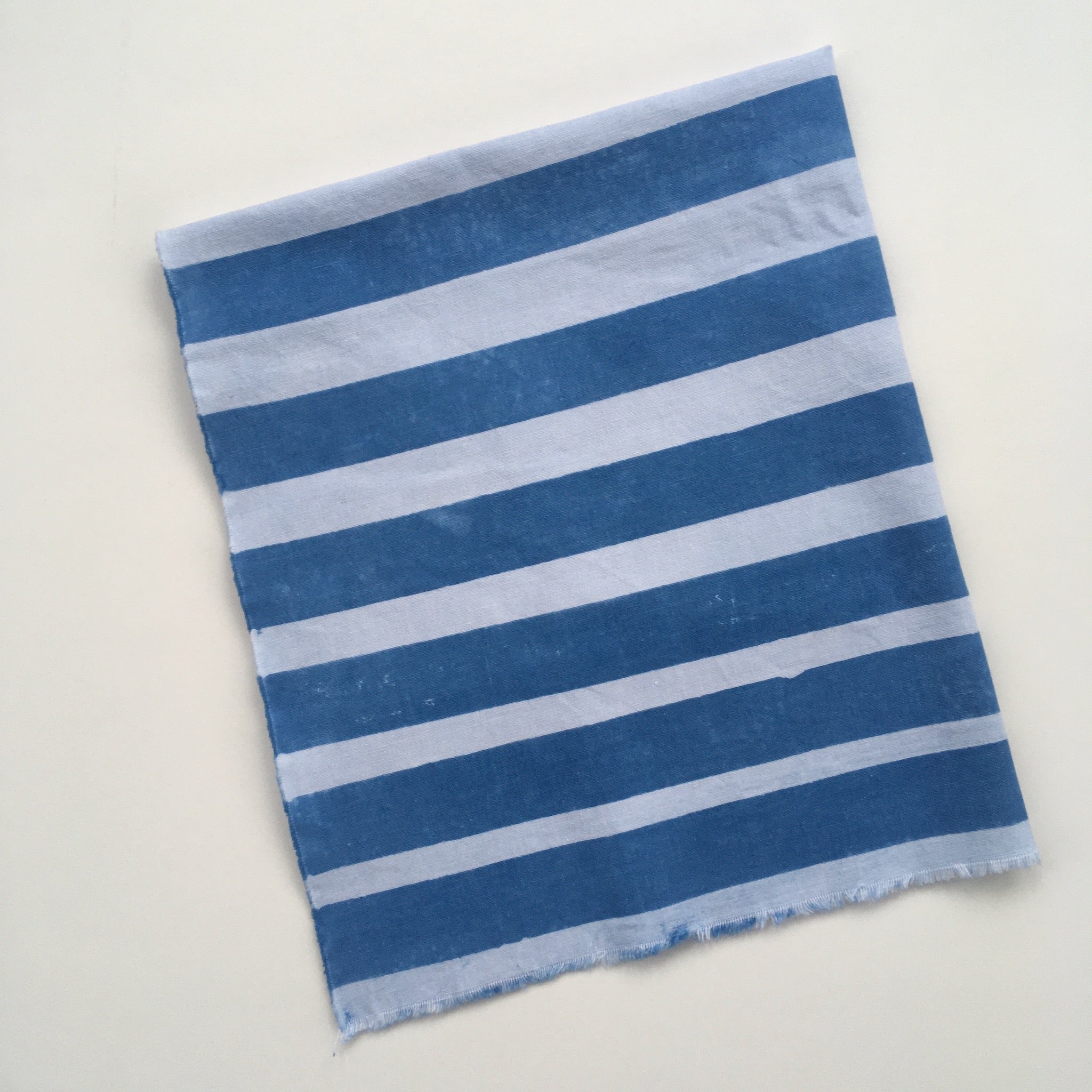 Fabric example dyed with clay resist: deep indigo blue with white stripes of varying width