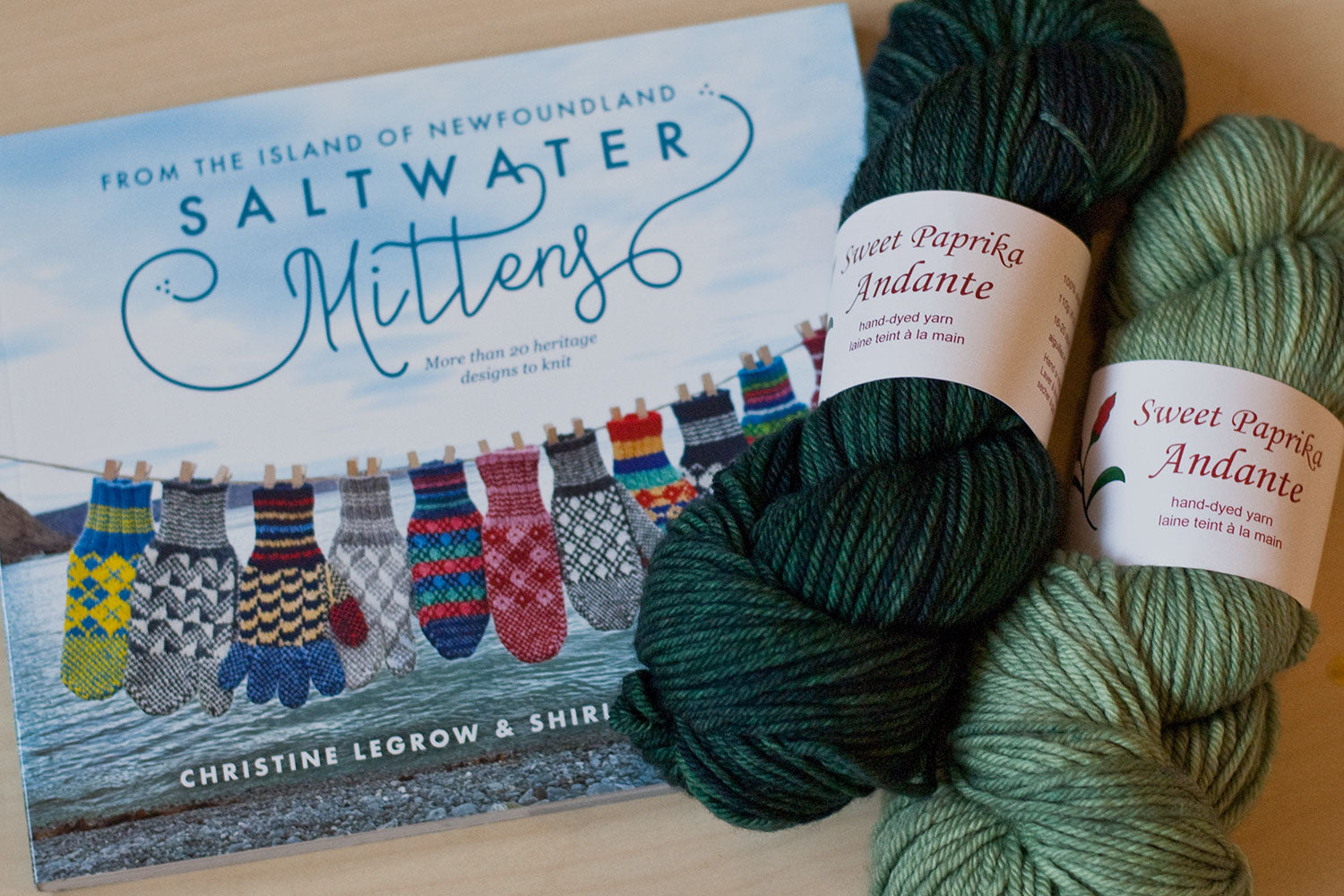 Saltwater Mittens book with two skeins of hand-dyed yarn in sage green and dark greenand-dyed yarn